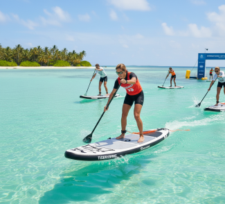 Women paddleboarding in a tropical race, blue waters and palm trees in the background, sunny day, competing athletes