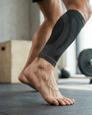 Person wearing a black calf compression sleeve while performing a workout in a gym setting, focusing on foot placement