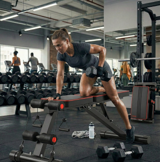 Woman performing dumbbell row exercise on adjustable bench in gym setting